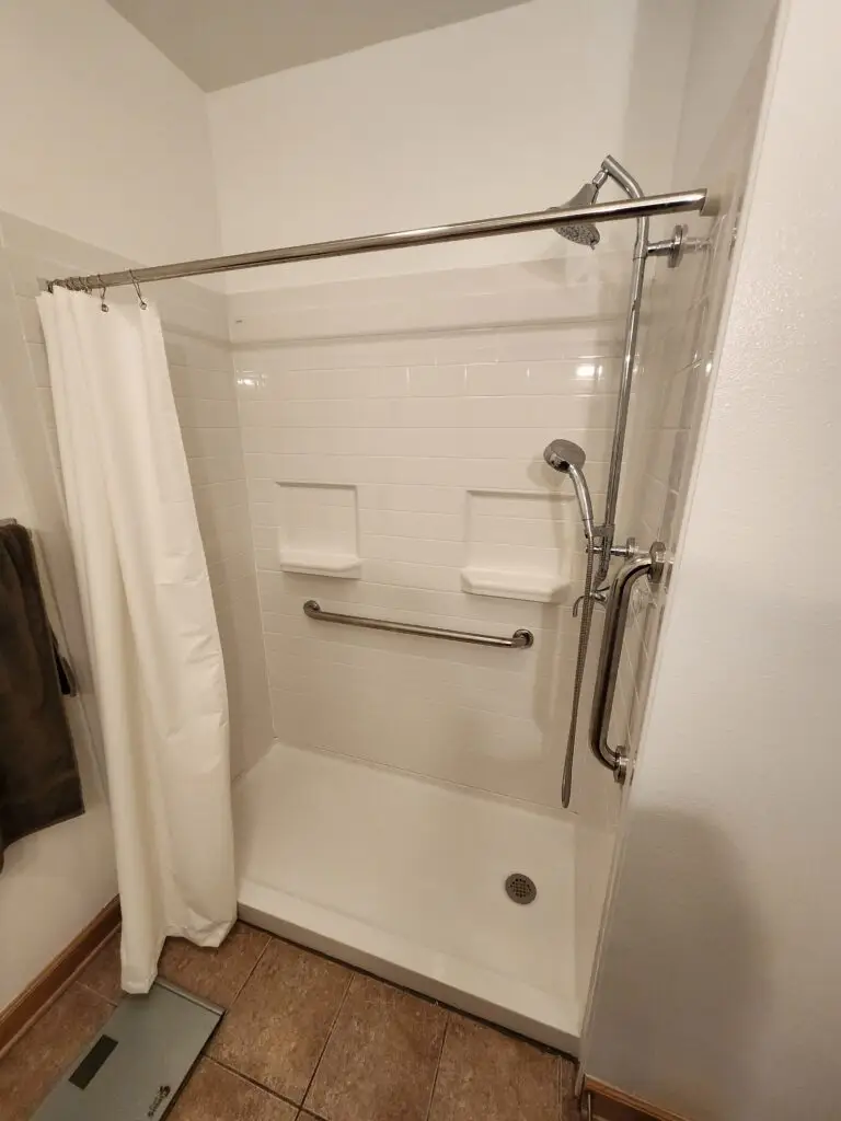 Photograph of a shower installation and remodel with grab bar and dual detachable hydro rail shower head system, completed by Adaptive Remodeling Solutions.