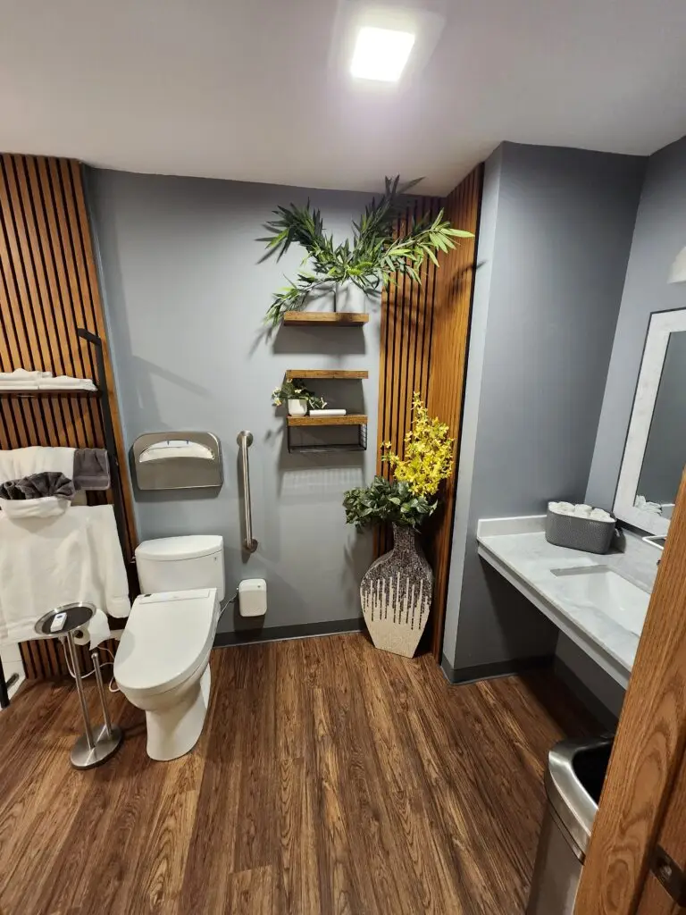 Photograph of a finished bathroom remodel completed by Adaptive Remodeling Solutions, including wooden accents, a grab bar near the toilet and a lowered sink