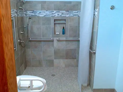 Photograph of a zero entry shower, three grab bars, and an adjustable hydro rail system shower head, installed by Adaptive Remodeling Solutions.