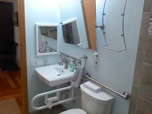 Photograph of a bathroom with a sink and a toilet with a handy cap grab bar, installed by Adaptive Remodeling Solutions.