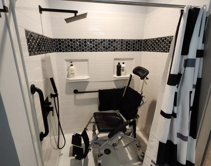 A wheelchair accessible shower unit installed by Adaptive Remodeling Solutions. This unit features a custom tile accent and rainfall shower head.