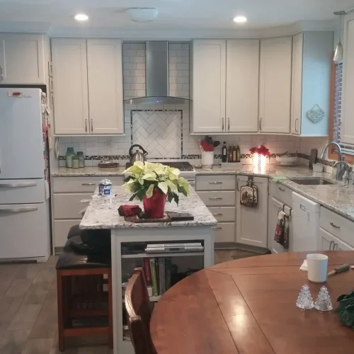 Photograph of a remodeled kitchen completed by Adaptive Remodeling Solutions, featuring white cabinets, an island, and large kitchen counter.